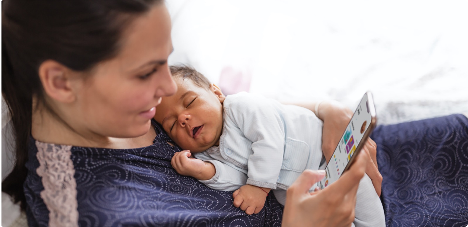 Mom holding infant and looking at phone